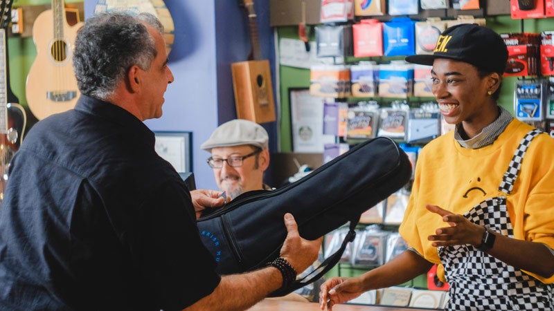 Man handing music instrument to lady in shop