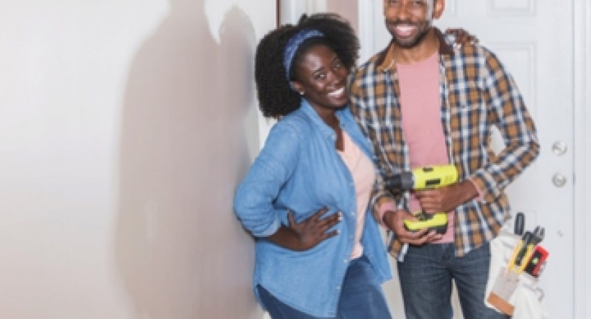 Photo of couple smiling and holding tools