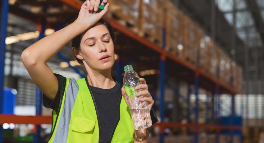 woman sweating and drinking water in warehouse 