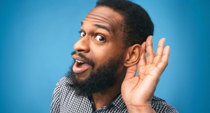 Man holding hand behind left ear to hear 