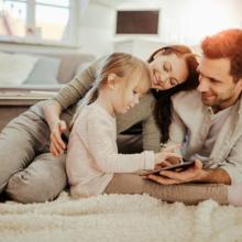 Woman and man next to little girl who is looking at ipad.