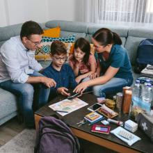 family on couch in living room all looking at a phone