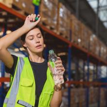 woman sweating and drinking water in warehouse 